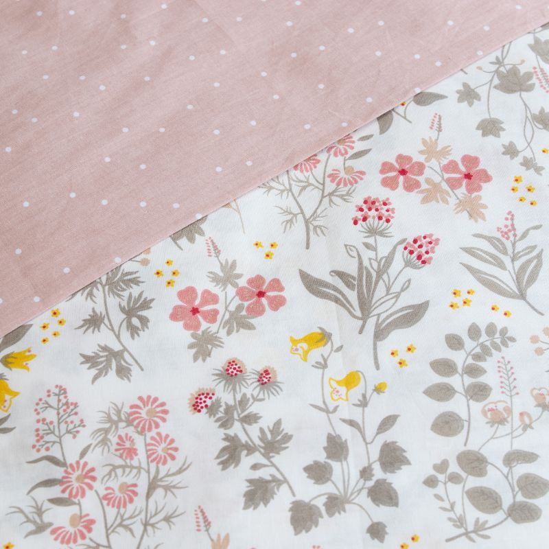 Close-up details of a soft pink quilt cover set featuring a delicate touch of spring, with blooms that dance softly across your bed.