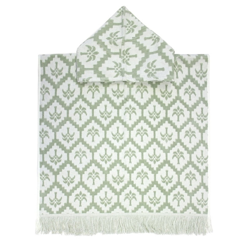 alt="Kids sage green poncho featuring a stylish palm tree pattern with knotted tassels along the ends"