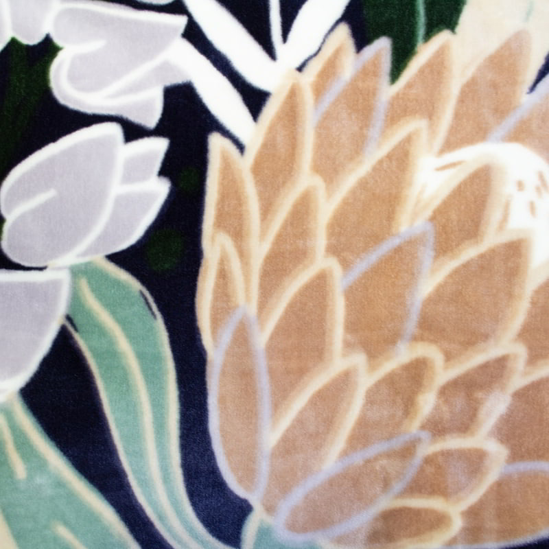 Fabric details of a blanket with a protea pattern on a navy blue backdrop with satin binding."