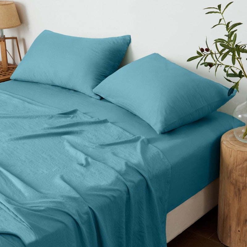 alt="A luxuriously soft slate blue cotton pre-washed sheet set in a cosy bedroom"
