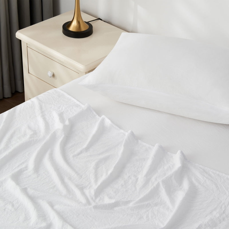 alt="A luxuriously soft white cotton pre-washed sheet set in a cosy bedroom"