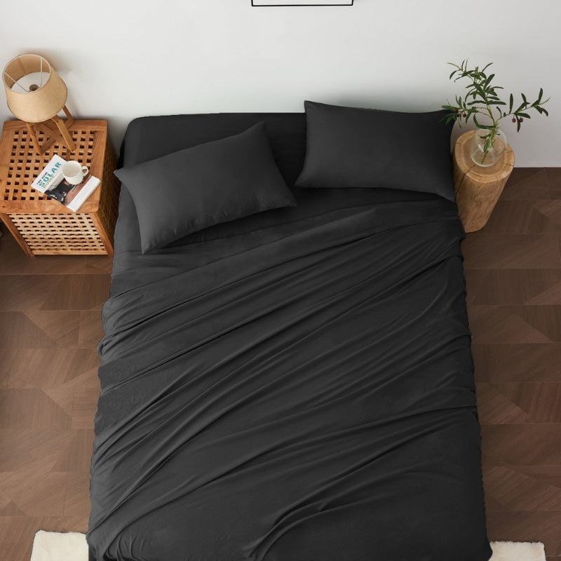alt="A luxuriously soft black cotton pre-washed sheet set in a cosy bedroom"