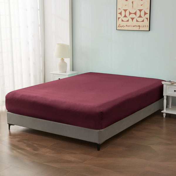 alt="An ultra-soft cotton blend burgundy fitted sheet with deep pocket in a cosy bedroom"