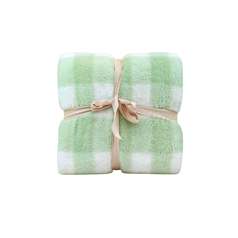 Front packaging details of a cosy bed with a green and white blanket featuring a large checkered pattern creates a bold visual grid, adding colour and pattern to the room's decor.