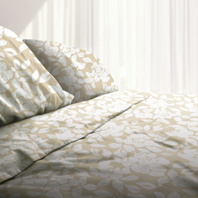 A natural-toned bed sheets and pillows, adorned with a monochromatic white floral and foliage pattern, craft a serene and unique design on a cosy bedroom.