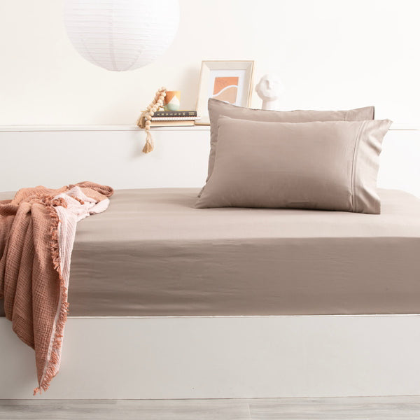 alt="Luxurious bed with a light brown sheet and pillow, made from a blend of bamboo and cotton for ultimate comfort."