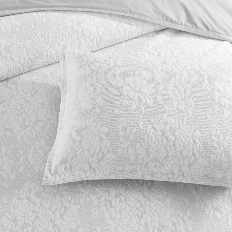alt="Close up details of an ivory quilt cover set infused with blooming flower bundles"