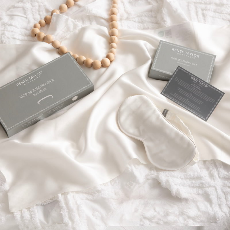 alt="A luxurious white satin eye mask with packaging box made from 100% pure mulberry silk. Wake up feeling refreshed and rejuvenated with this gentle and hydrating mask."