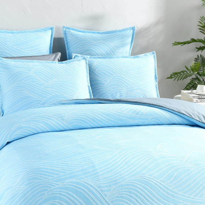 alt="Showcasing a shades of blue quilt cover with a beach wave design."