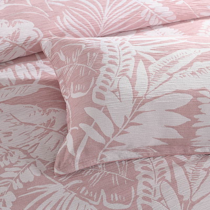 alt="Showcasing a close up details of shade of pink european pillowcase featuring intricate island themes with swaying palm trees in tropical rainforest"