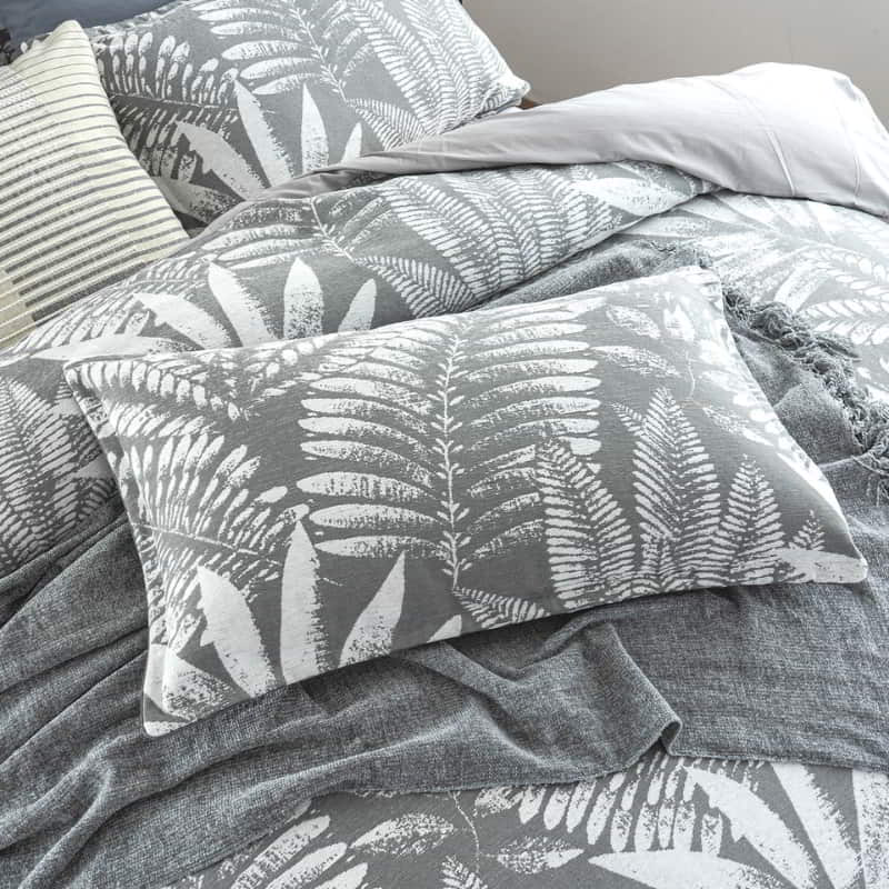 alt="A luxurious, eclectic mix of modern and conventional design pillowcase that creates a tropical retreat with lush leaves."