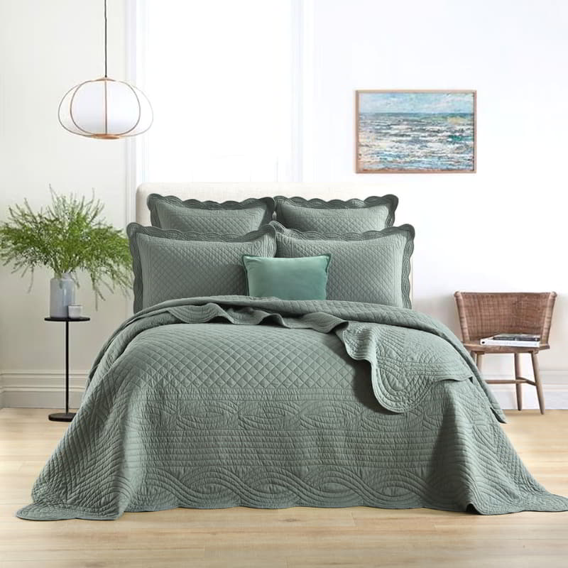 alt="A tone of green european pillowcase and quilt cover with a nod to French quilting tradition and decorative details like scallop edges in a luxurious bedroom."