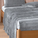 A modern bedroom with a beige upholstered bed and cream bedding exudes winter comfort, enhanced by the Morgan and Reid Winter Microplush Sheet Sets ultra-soft fabric, neutral decor, dried flowers, and light wood floors.