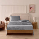 A modern bedroom with a beige upholstered bed and cream bedding exudes winter comfort, enhanced by the Morgan and Reid Winter Microplush Sheet Sets ultra-soft fabric, neutral decor, dried flowers, and light wood floors.