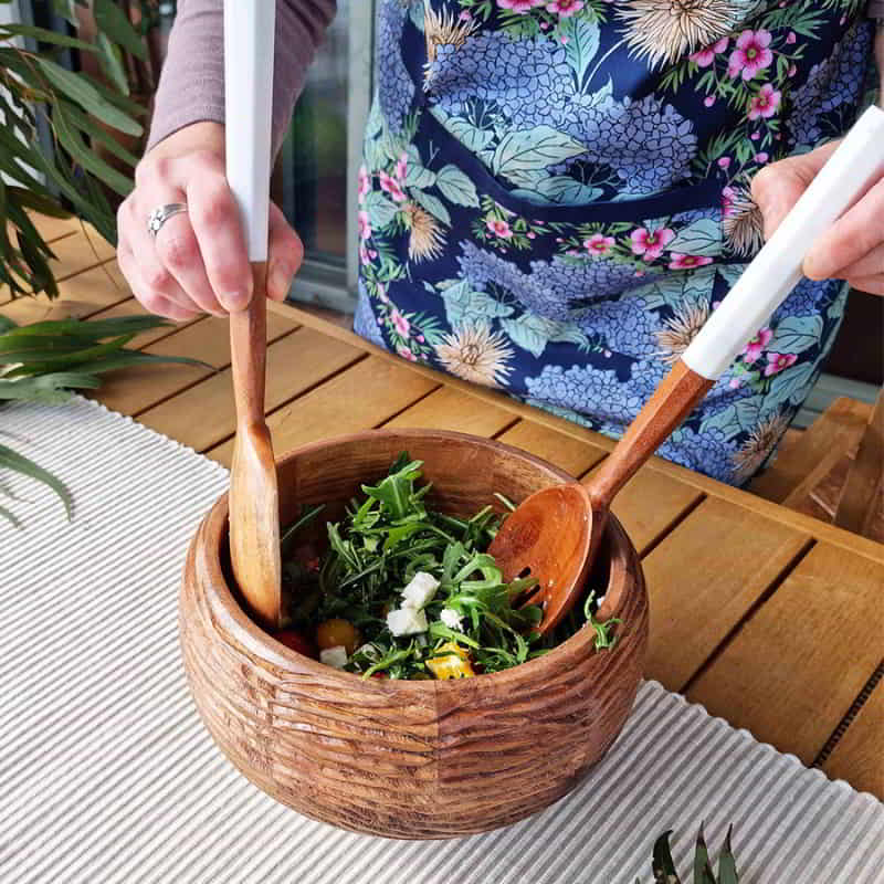 alt="A navy apron features beautiful flowers and colours of an Australian summer garden used by the woman in the dining area"