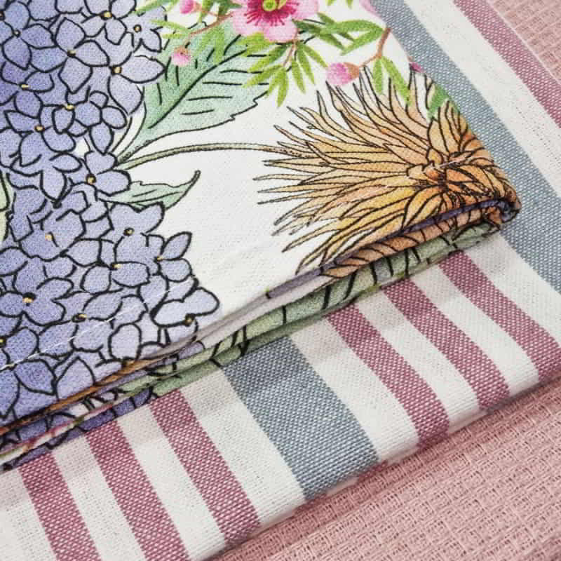 alt="Zoom in details of 3 pieces of pink tea towels featuring one printed design, one striped design and one plain waffle."