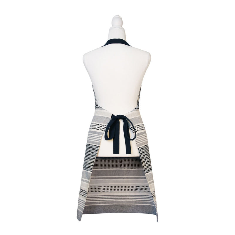 alt="Back details of a navy and grey apron featuring a combination of stripes and stitches in a neutral colour palette."