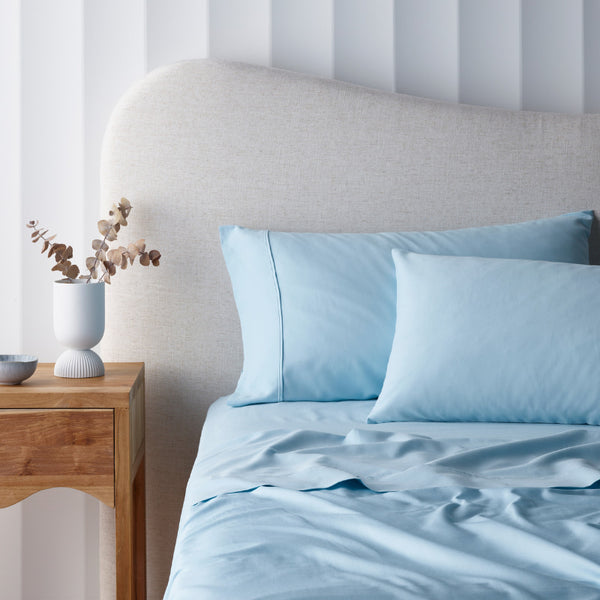 alt="A blue cotton rich sheet set in a luxurious bedroom"