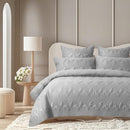 Grey bamboo cotton coverlet set styled on a bed with matching pillows in a bright, neutral bedroom