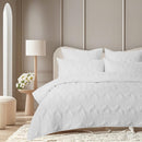 Full view of the coverlet set on a bed styled in a bright, minimalist bedroom setting