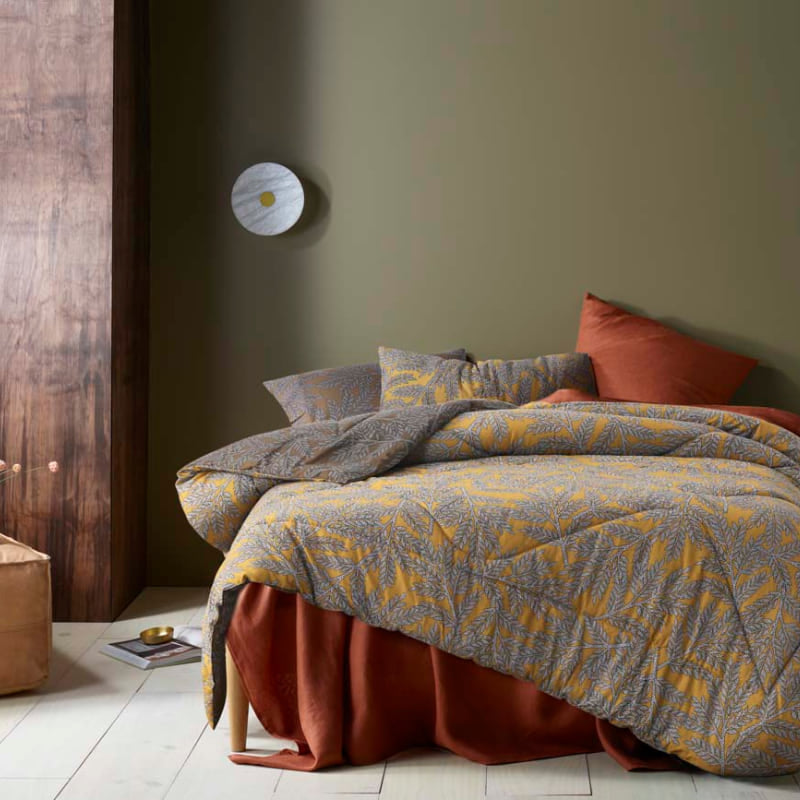 alt="A cotton-printed comforter set with tropical clove leaves pattern in a cosy bedroom"