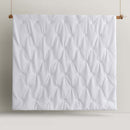 Detailed shot of a textured jacquard comforter set in classic white with clipped dot detail, and polyester filled with quilting for warmth.