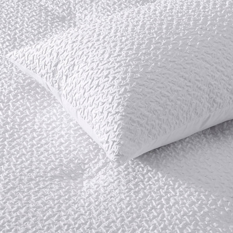 Zoom in details of a textured jacquard comforter set in classic white with clipped dot detail, and polyester filled with quilting for warmth.