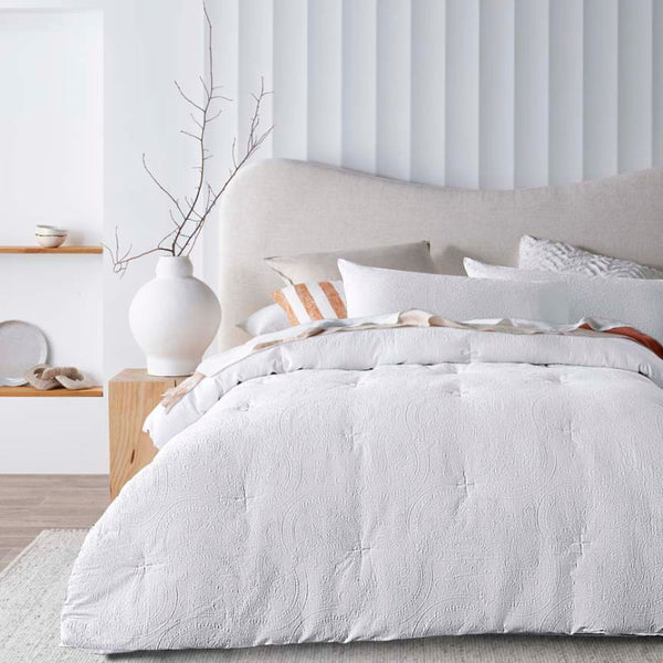 alt="A comforter set featuring a stunning timeless white jacquard design on a cosy bedroom"