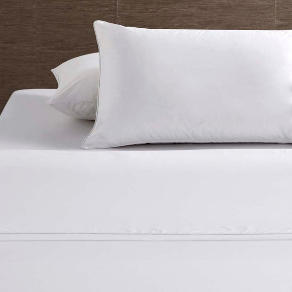 alt="White deluxe cotton sheet set and pillowcases in a cosy bedroom"