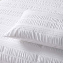 alt="Zoom in details of a white quilt cover set gives the classic look of crisp white bed linen while the texture ensures your bedroom looks anything but basic along with the pillowcases."