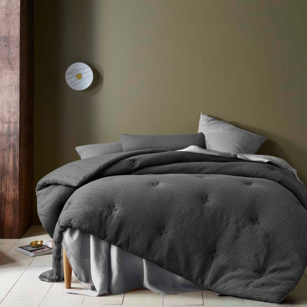 alt="A dark grey quilt cover set featuring a detailed geometric design created using a three-dimensional weaving technique"