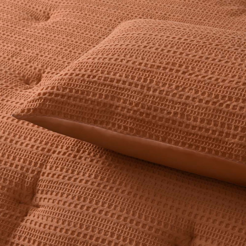 alt="Zoom in details of a brown comforter set featuring a detailed geometric design created using a three-dimensional weaving technique along with the pillowcases"