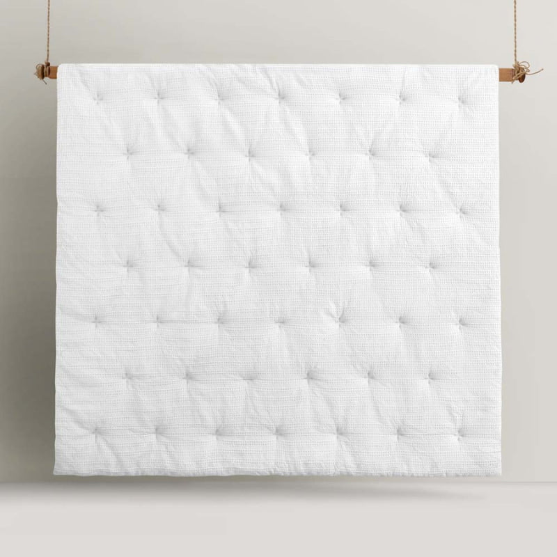 alt="Front details of a white comforter set featuring a detailed geometric design created using a three-dimensional weaving technique"
