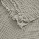 alt="Close-up details of a natural throw featuring a 4 layer gauze cotton fabric with natural frayed edge"