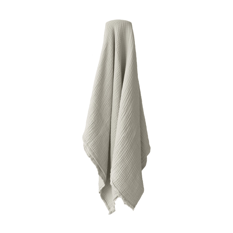 alt="A natural throw featuring a 4-layer gauze cotton fabric with a natural frayed edge"