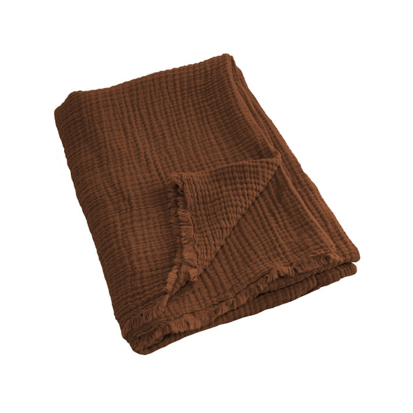 alt="A rust throw featuring a 4 layer gauze cotton fabric with natural frayed edge"