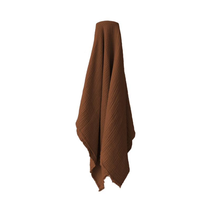 alt="A rust throw featuring a 4 layer gauze cotton fabric with natural frayed edge"