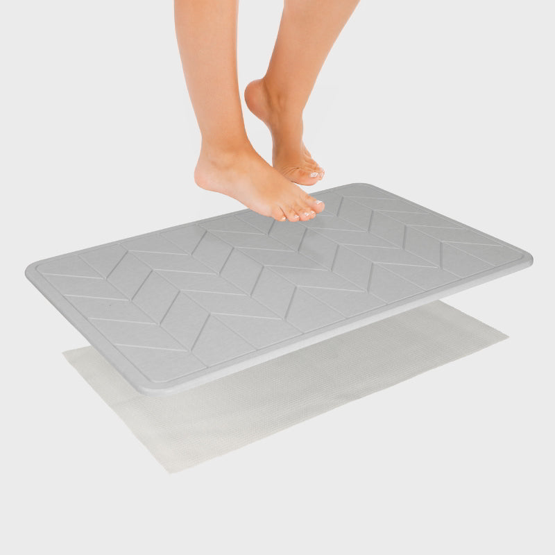 Someone is stepping at a light grey bath stone with its super porous surface, keeps your floor clean and dry, minimizing bacteria growth.