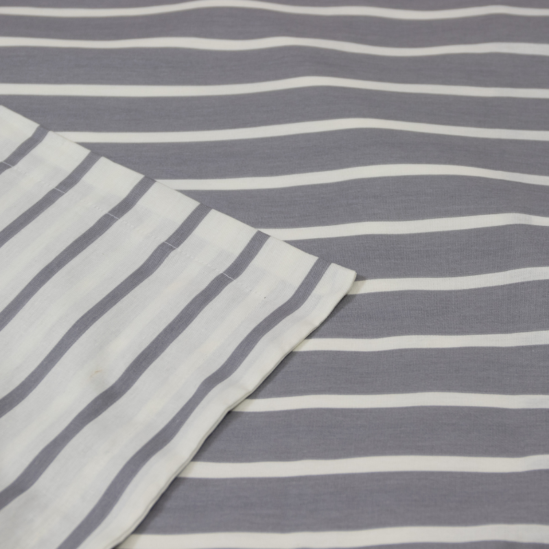 Detailed view of a grey and white striped quilt cover, highlighting its contemporary style and cosy appeal in a modern bedroom.