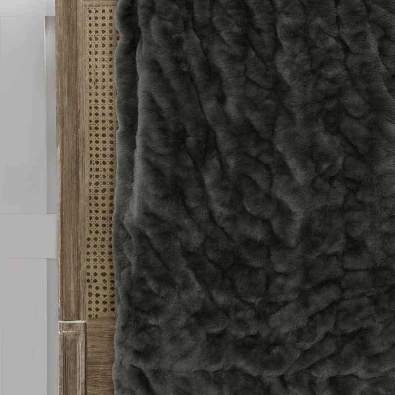 Close-up details of a luxurious khaki throw with a soft, plush texture and earthy colour, featuring a green throw with a black trim.