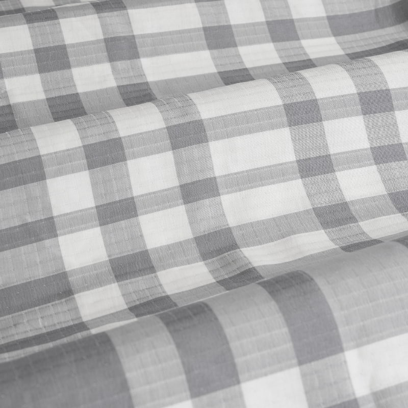 Detailed view of a grey checkered fabric, highlighting the timeless plaid pattern ideal for a warm bedroom vibe.
