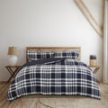 A cosy bed adorned with a navy and white plaid comforter, enhancing the room's classic charm and inviting relaxation.