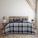 A cosy bed adorned with a navy and white plaid comforter, enhancing the room's classic charm and inviting relaxation.