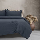 A beautifully arranged bed with vintage washed navy sheets, adding a touch of warmth and comfort to the bedroom decor.
