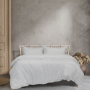 A cosy bed with white sheets and pillows, showcasing the soft Ardor Boudoir Vintage Washed White Quilt Cover Set.