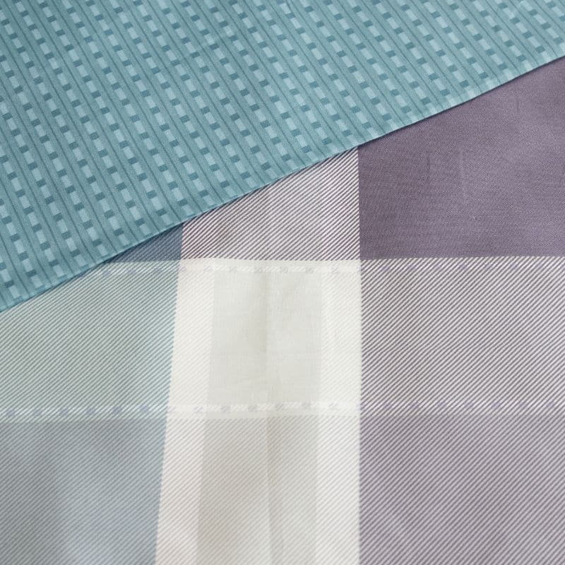 Detailed view of a soft blues and muted purples in a layered check pattern with subtle textured detail quilt cover set.