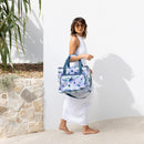 A woman in a white dress carries a large cooler bag, perfect for picnics and gatherings, showcasing its stylish design.