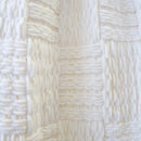 Close-up of a white woven texture and yarn detail on the Asha Throw