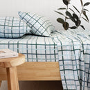 Bambury Campbell flannelette sheet set styled on a wooden bed with check print in blues and greens