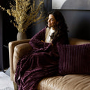 Bambury Channel Plum Cushion styled on a bed with matching throw